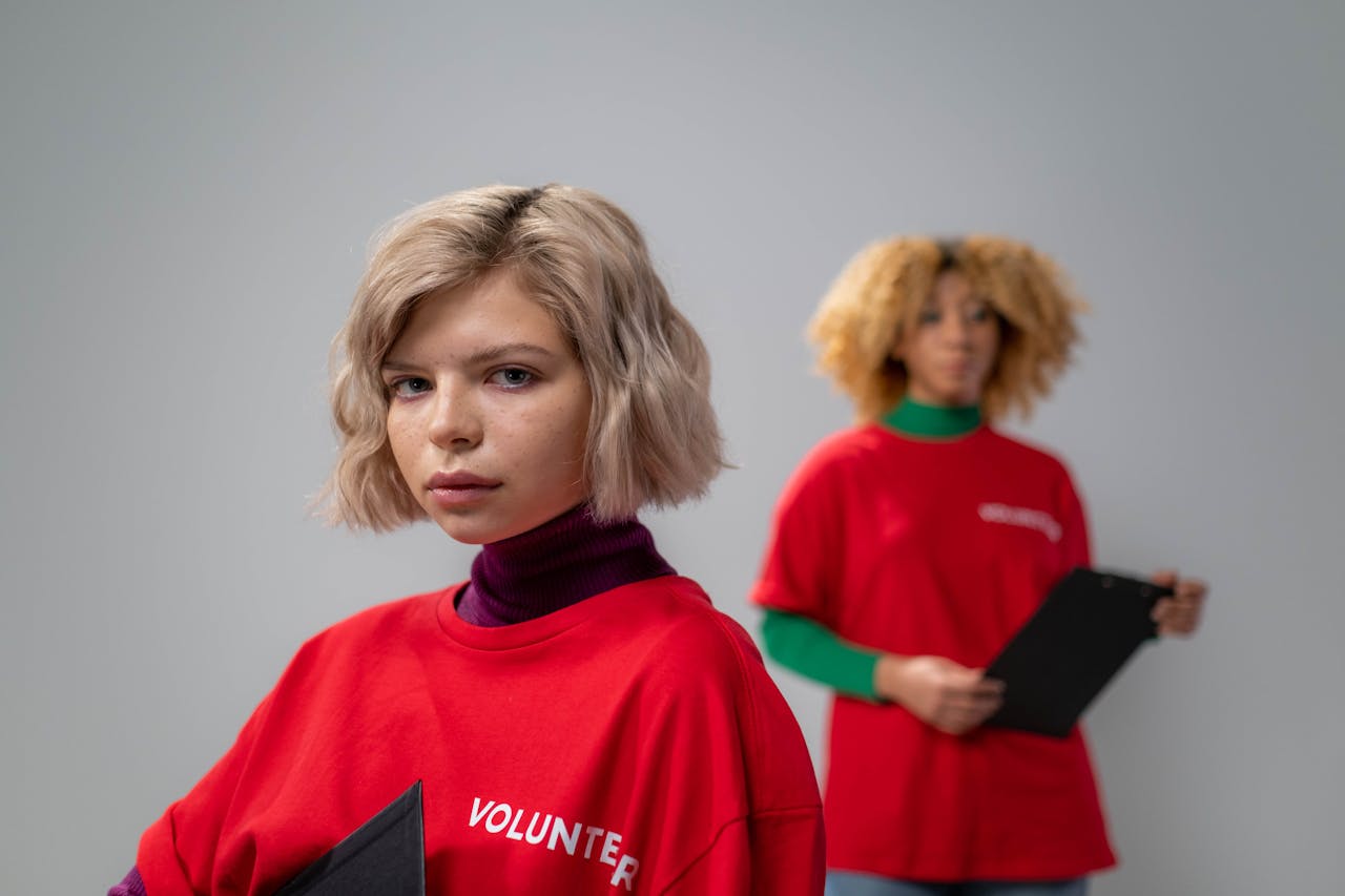 Two young female volunteers in red shirts during community service indoors.